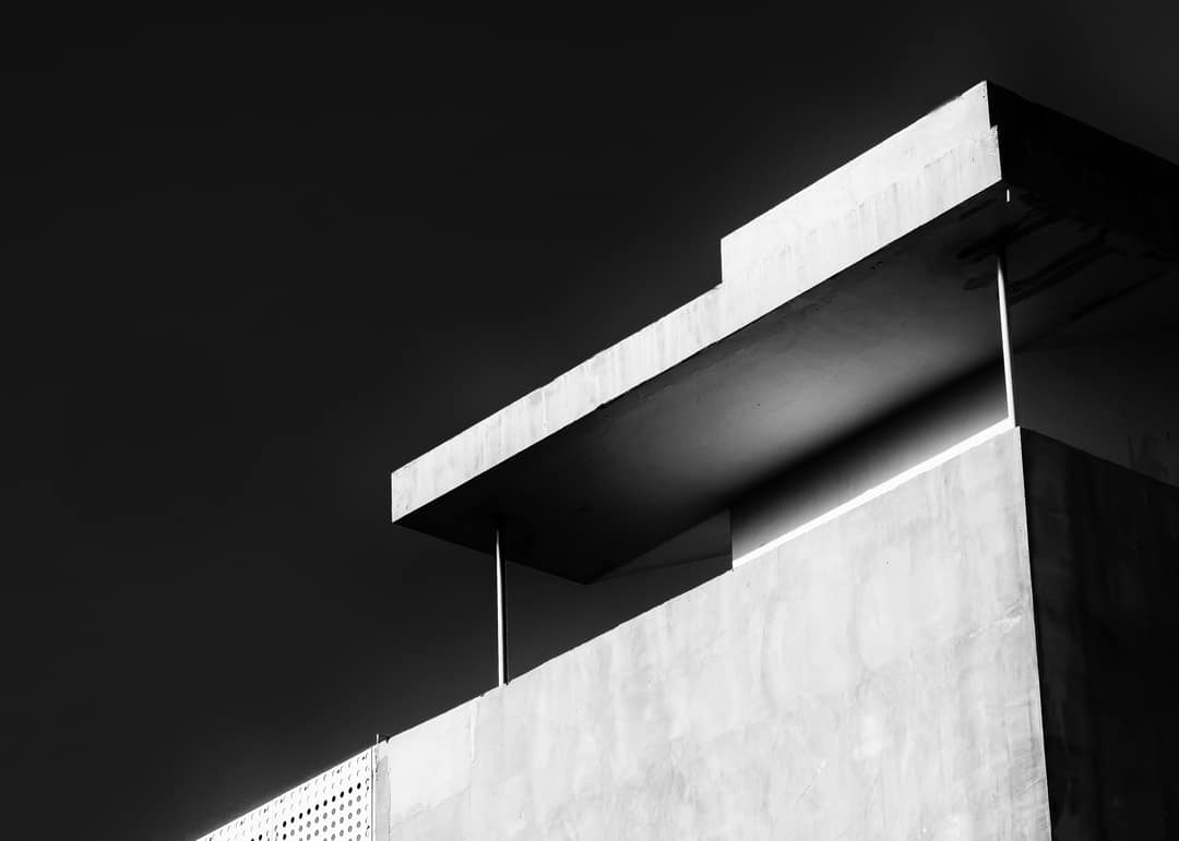 A cantilevered concrete slab against a black sky, in black and white