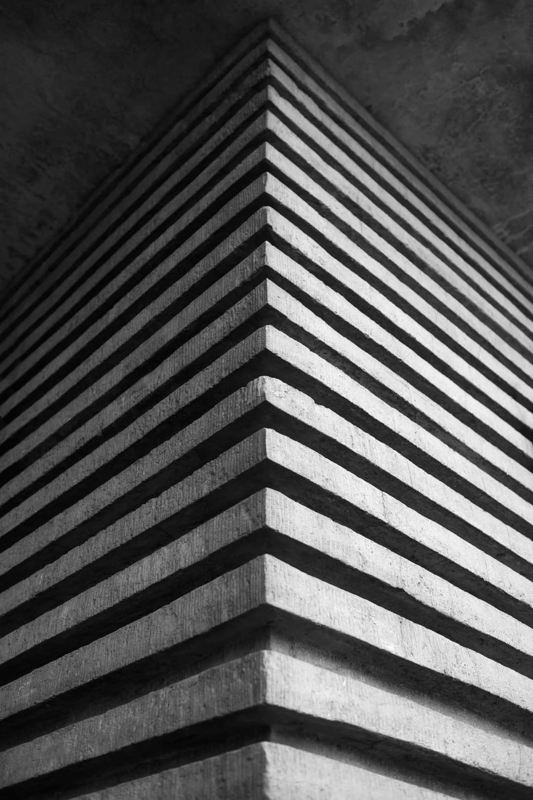 The corner of a ribbed concrete building, in black and white